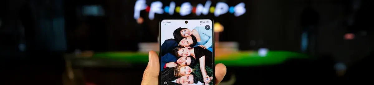 A mobile phone showing the cast of Friends with the Friends logo in the background